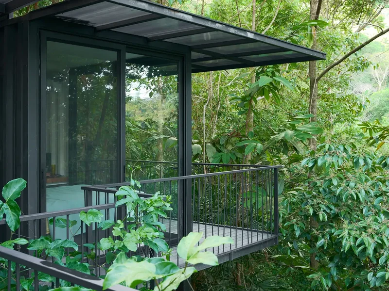 Glass-walled bedroom and steel balcony at Casa Alba overhanging the jungle